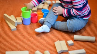 Ein Kind spielt mit Plastikbechern und Holzklötzchen Ein Kind spielt mit Plastikbechern und Holzklötzchen