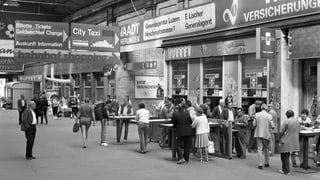 Schwarzweiss-Bild aus dem Jahr 1987. Menschen stehen im Bahnhof Luzern.