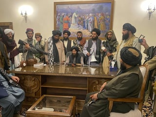 Auf kleinem Raum sind vierzehn Taliban-Anhänger zu sehen, einer sitzt dabei offenbar auf dem Präsidentenstuhl. Fast alle tragen eine Waffe. Eine Kalaschnikov scheint demonstrativ auf dem Tisch zu liegen.