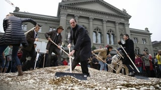 Die Initianten für ein bedingungsloses Grundeinkommen schaufeln 5-Räppler Haufen auf dem Bundesplatz. Die Initianten für ein bedingungsloses Grundeinkommen schaufeln 5-Räppler Haufen auf dem Bundesplatz.