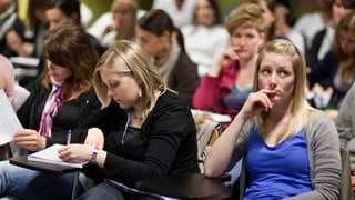 Arbeitende und nachdenkende Studierende in einem Hörsaal der Uni Basel. 