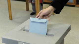 Jemand steckt ein Couvert in eine Wahlurne in Österreich