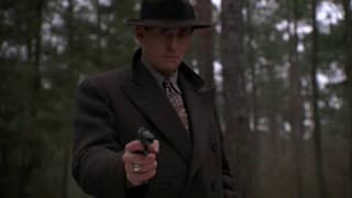 Ein Mann mit Hut zielt mit einer Pistole in Richtung Kamera