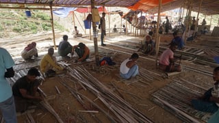 Menschen in einer provisorischen Unterkunft, bauen selber ihre Hütten.