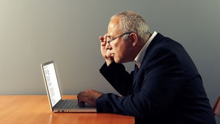 Ein Mann betrachtet aufmerksam eine Internetseite auf seinem Laptop