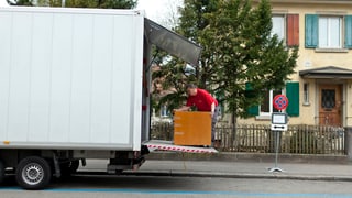 Ein Zügelmann hantiert mit einem Möbelstück auf der Hebebühne eines Umzug-Lastwagens.