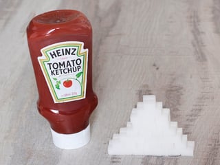 Ketchup-Flasche neben einem Turm Würfelzucker.