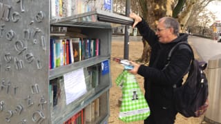 Mann mit Rucksack und Bücher in der Hand hebt Tür eines Regals auf. Mann mit Rucksack und Bücher in der Hand hebt Tür eines Regals auf.