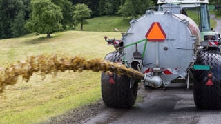 Traktor zieht Güllefass und schiesst Gülle auf Feld Traktor zieht Güllefass und schiesst Gülle auf Feld