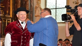 Mann steckt Preisträger eine Nadel ins Revers. Mann steckt Preisträger eine Nadel ins Revers.