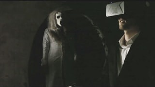 Ein Mann blickt in eine VR-Brille, im Hintergrund steht eine Zombie-Frau.