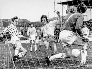 Schwarz-Weiss-Fotografie mit fünf Fussballspielern vor einem Tor.