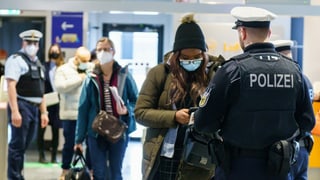 Polizisten kontrollieren Einreisende am Flughafen.