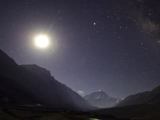Weit entfernter Gipfel des Mount Everest in der Nacht. Der Mond leuchtet hell.