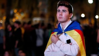 Junger Mann mit katalanischer Fahne über den Schultern.
