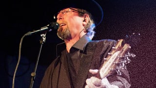Roger McGuinn am Mikrofon mit Gitarre.