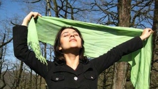 Iranische Frau hält ihren Schleier in die Luft