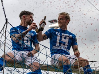 Zwei Rostock-Spieler sitzen auf dem Torgehäuse und trinken ein Bier.