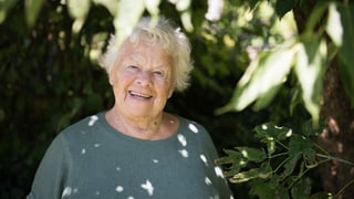 Ältere Frau steht im Schatten eines Baumes Ältere Frau steht im Schatten eines Baumes