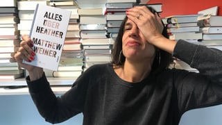 Annette König hält den Roman «Alles über Heather» von Matthew Weiner in der Hand und greift sich mit der andern Hand an den Kopf