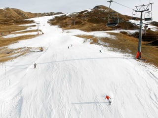 Skipiste in grün, eine Schneise ist beschniet und ein paar Wintersportler darauf unterwegs. Skipiste in grün, eine Schneise ist beschniet und ein paar Wintersportler darauf unterwegs.