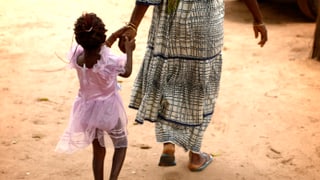 Frau in Afrika führt kleines Mädchen in rosa Kleidchen an der Hand. Frau in Afrika führt kleines Mädchen in rosa Kleidchen an der Hand.