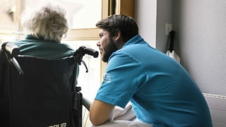 Zivildienstleistender bei einer alten Dame im Rollstuhl. 