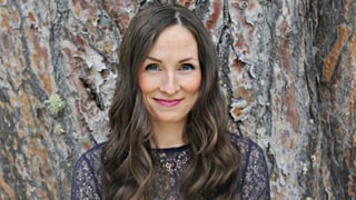 Porträt von Julie Fowlis vor einem Baumstamm. 