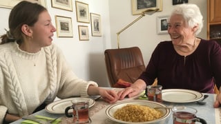 Eine junge und eine ältere Frau sitzen gemeinsam am gedeckten Tisch. Eine junge und eine ältere Frau sitzen gemeinsam am gedeckten Tisch.