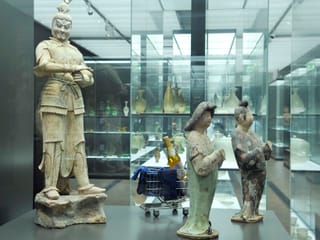 Chinesische Statuen in gläsernem Entrée, ein Einkaufswagen im Hintergrund