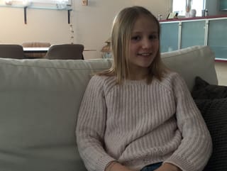 Ein Mädchen sitzt auf dem Sofa und lacht