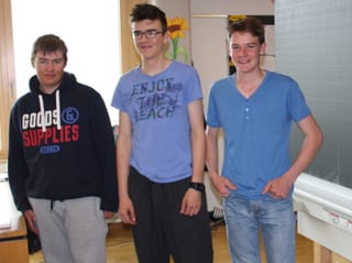 Drei junge Burschen vor der Wandtafel in einem Klassenzimmer.