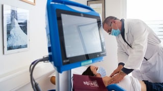 Arzt untersucht im Krankenhausbett Long-Covid-Patientin