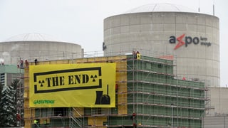 Aktivisten von Greenpeace montieren ein gelbes Plakat mit der Aufschrift «The End» am AKW.
