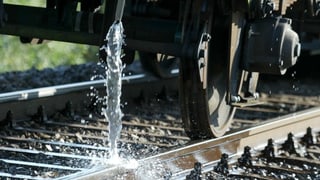 Ein Zug begiesst Schienen mit Wasser.