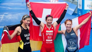 Nicola Spirig hält jubelnd die Schweizer Fahne in die Höhe, an ihrer Seite stehen die Silber- und Bronze-Medaillengewinnerinnen. 