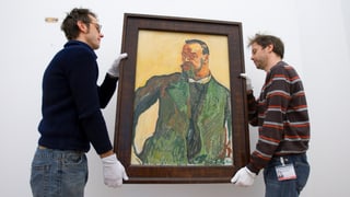 2 Mitarbeiter hängen ein Bild auf 2 Mitarbeiter hängen ein Bild auf