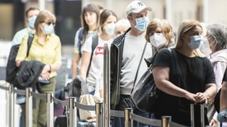 Passagiere mit Schutzmasken am Flughafen Zürich.