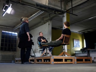 Personen sitzen und stehen am Set.