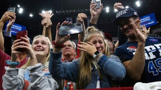 Fans von Donald Trump halten Handys hoch, eine junge Frau wischt sich Tränen ab. Fans von Donald Trump halten Handys hoch, eine junge Frau wischt sich Tränen ab.