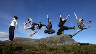 Sechs Tänzerinnen und Tänzer springen in freier Natur in einer markanten Pose in die Luft. Sechs Tänzerinnen und Tänzer springen in freier Natur in einer markanten Pose in die Luft.