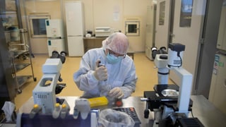 Ein Mann in Schutzkleidung und einer Maske arbeitet in einem Labor.