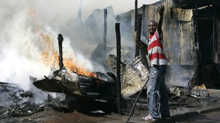 Ein Anhänger der Opposition steht vor einem abgebrannten Haus im Kibera-Slum von Nairobi.