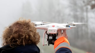 Ein Pilot hält seine Drohne in der Hand. 