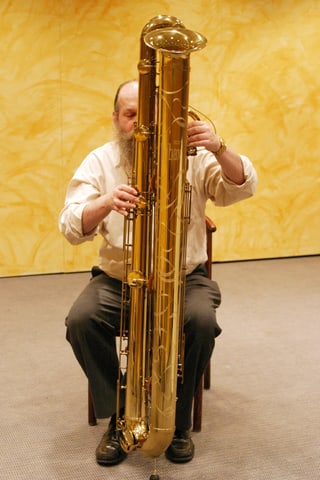 Ein Mann spielt auf einem grossen, fast mannshohen Blasinstrument. Ein Mann spielt auf einem grossen, fast mannshohen Blasinstrument.