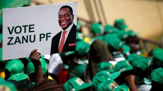 Menschenmenge mit grünen Hüten, ein Plakat mit Mnangagwa in der Menge.