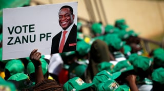 Menschenmenge mit grünen Hüten, ein Plakat mit Mnangagwa in der Menge. Menschenmenge mit grünen Hüten, ein Plakat mit Mnangagwa in der Menge.