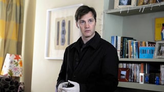 Ein Mann mit Gummihandschuhen steht in einem Zimmer.