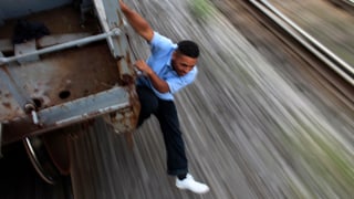 Ein Mann springt von einem fahrenden Zug. 
