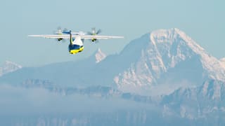 Flugzeug nach dem Start, im Hintergrund die Alpen.